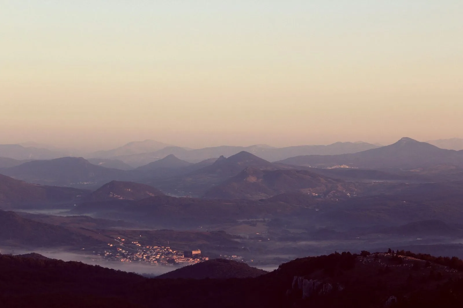 Profili di montagne dell'Alto Molise all'alba con la nebbia nelle valli e un paese illuminato dal sole