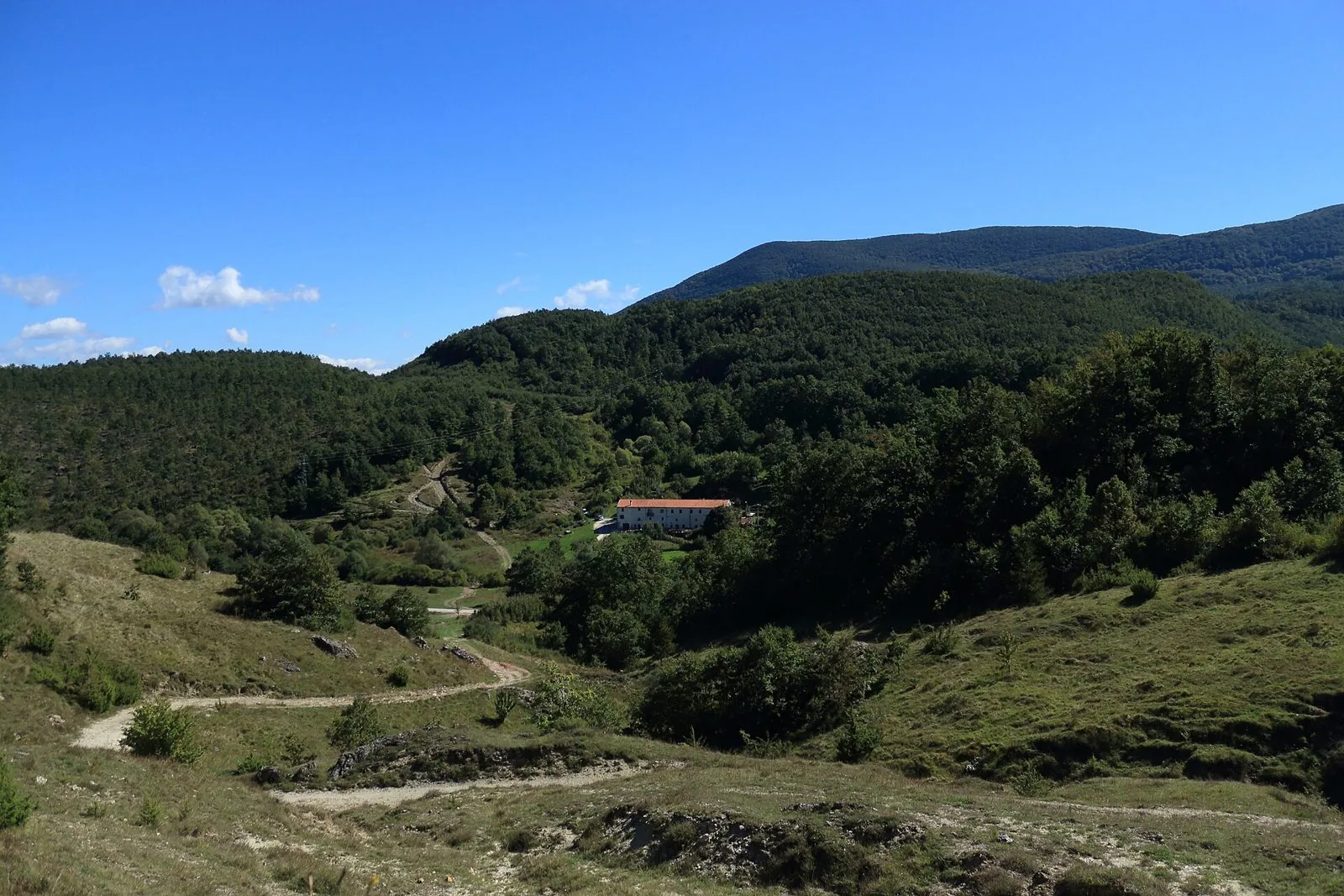 Pascoli e sentieri sul tratturo Castel di Sangro-Lucera, con un antico edificio bianco detto Tavernola tra i boschi dell'Alto Molise
